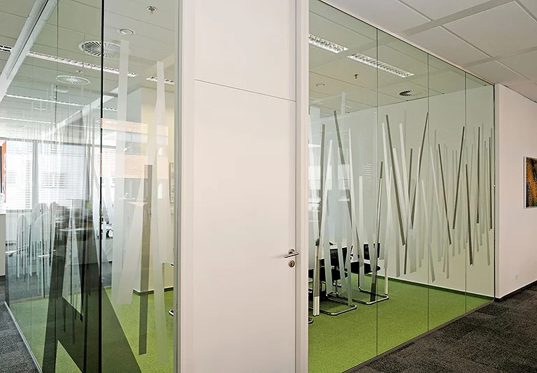 Moderne Büroräume mit Glastrennwänden, weißer Tür und grünem Teppichboden, dekorative Streifenfolien auf Glas
