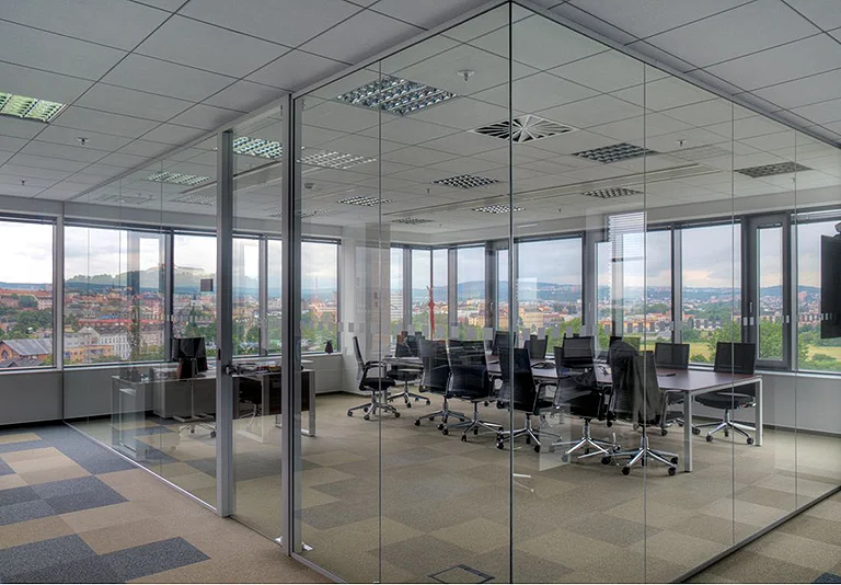 Moderner Büroraum mit Glastrennwänden, Konferenztisch mit schwarzen Stühlen und Panoramafenstern mit Stadtblick