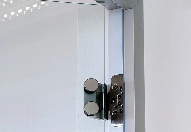 Edelstahl-Scharnier mit zwei runden Abdeckkappen an einer Glastrennwand montiert, Detailaufnahme