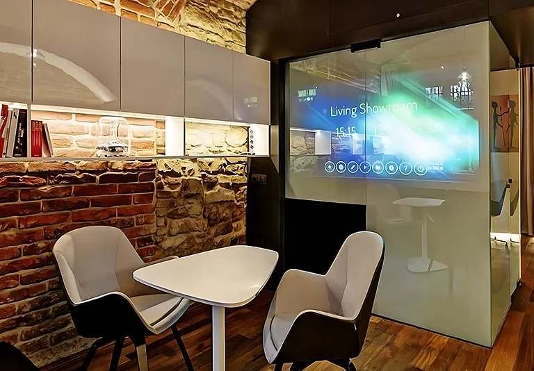 Moderner Showroom mit Steinwand, weißen Möbeln und interaktivem Display an Glaswand