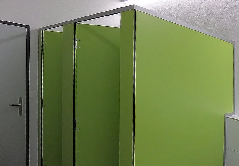 Grüne Toilettenkabinen-Trennwände aus Kompaktlaminat in einem Sanitärraum mit weißen Wänden
