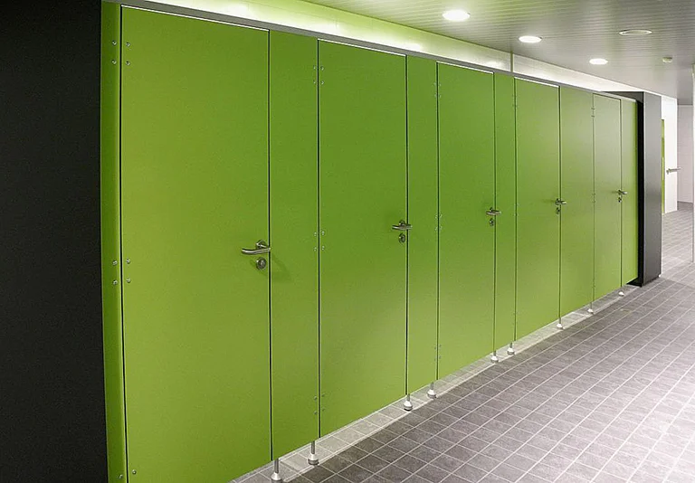 Grüne WC-Trennwände in einer Reihe mit silbernen Türgriffen und Beschlägen in einem modernen öffentlichen Sanitärraum